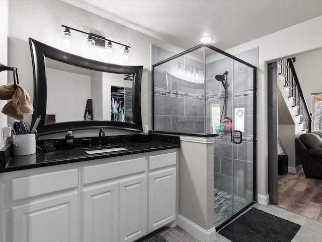 full bath featuring a shower stall, vanity, and baseboards