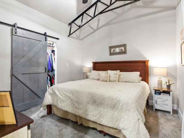 bedroom featuring a barn door, baseboards, a walk in closet, and carpet