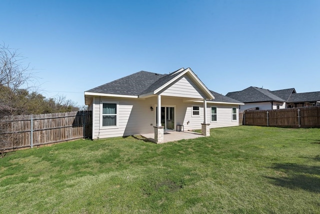 back of house featuring a patio, a fenced backyard, a lawn, and a shingled roof