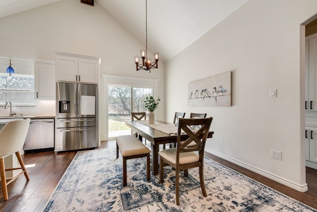 dining room featuring dark wood-type flooring, a notable chandelier, baseboards, and high vaulted ceiling