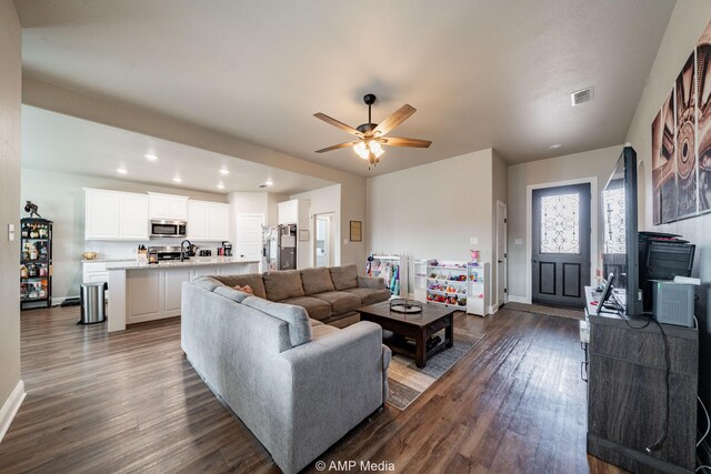 living area featuring a ceiling fan, baseboards, visible vents, dark wood finished floors, and recessed lighting