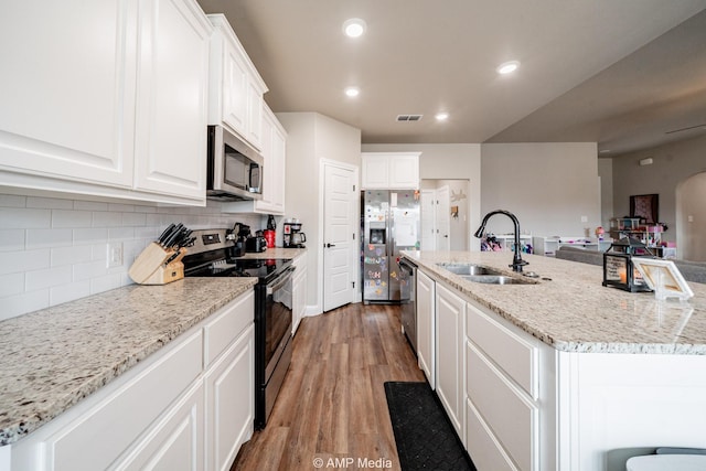 kitchen with a sink, tasteful backsplash, white cabinetry, recessed lighting, and appliances with stainless steel finishes