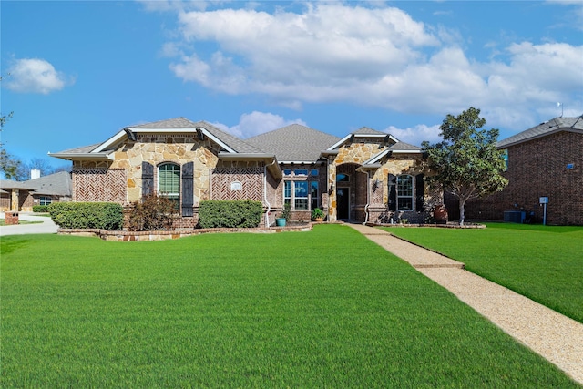 view of front of home with a front lawn, brick siding, stone siding, and central AC