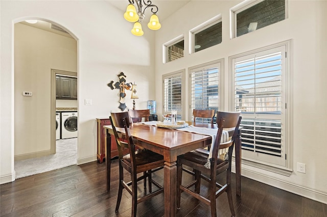 dining room with arched walkways, dark wood-style flooring, a high ceiling, and separate washer and dryer