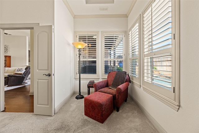 sitting room with visible vents, baseboards, crown molding, and carpet