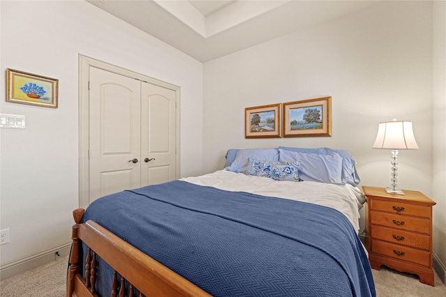 bedroom with a closet, baseboards, and light colored carpet