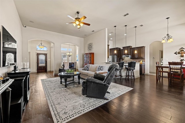 living room with visible vents, dark wood finished floors, a high ceiling, arched walkways, and ceiling fan with notable chandelier