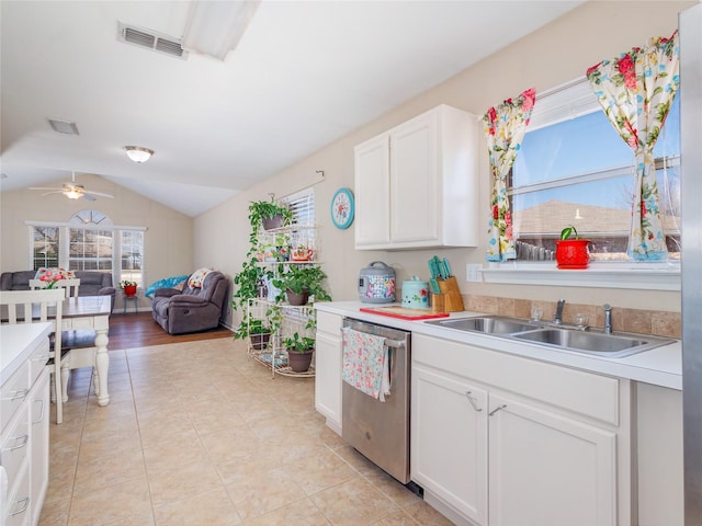 kitchen featuring visible vents, a sink, white cabinets, lofted ceiling, and dishwasher