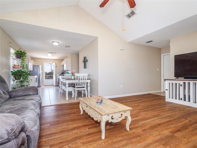 living area featuring visible vents, baseboards, light wood-type flooring, and lofted ceiling