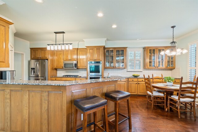 kitchen featuring glass insert cabinets, crown molding, brown cabinetry, and stainless steel appliances