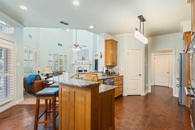 kitchen featuring visible vents, a breakfast bar, stainless steel appliances, and brown cabinetry