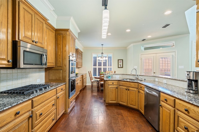 kitchen featuring visible vents, a sink, stainless steel appliances, brown cabinetry, and light stone countertops