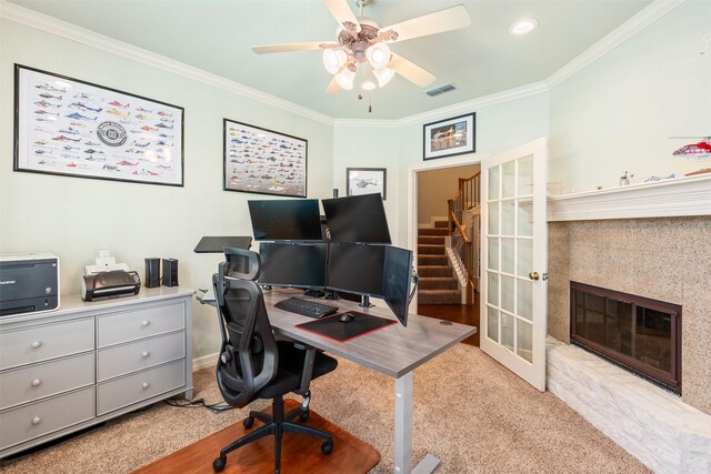 carpeted office with a ceiling fan, crown molding, a fireplace, and visible vents