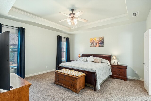 bedroom with a tray ceiling, visible vents, and light carpet