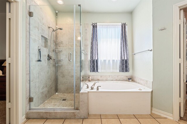 full bath with tile patterned floors, a bath, baseboards, and a stall shower