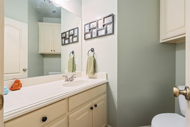 bathroom featuring visible vents, toilet, and vanity