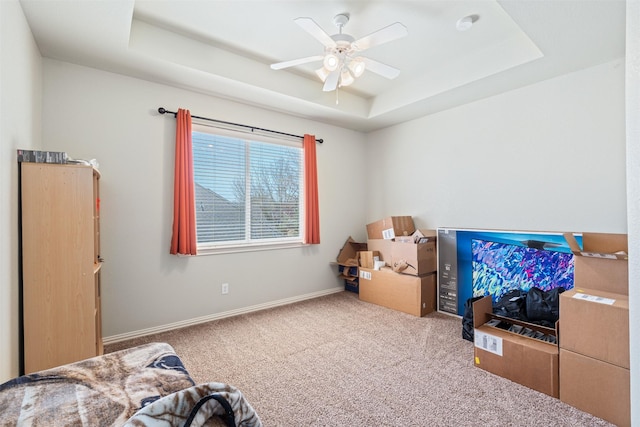 bedroom with baseboards, a raised ceiling, carpet, and a ceiling fan