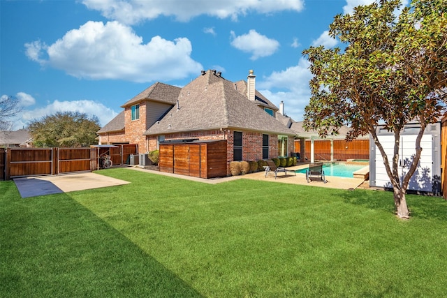 rear view of property with a yard, a patio, brick siding, and a fenced backyard