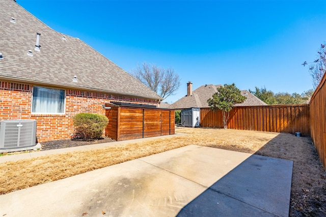 view of patio featuring an outdoor structure, a storage unit, central AC unit, and a fenced backyard