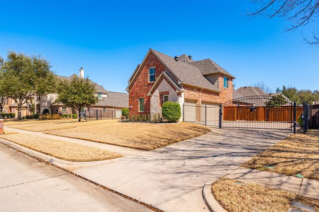 view of front of house featuring fence, brick siding, driveway, and a gate