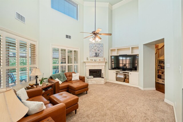 carpeted living area with visible vents, a fireplace, a ceiling fan, and ornamental molding