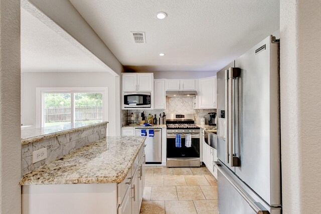 kitchen with visible vents, backsplash, under cabinet range hood, appliances with stainless steel finishes, and white cabinets