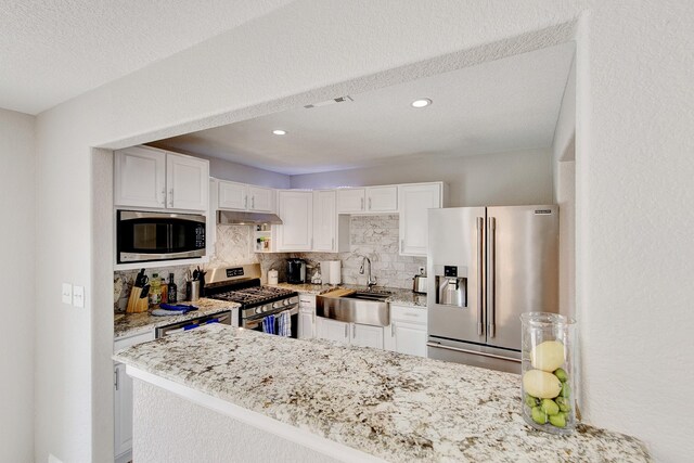 kitchen with under cabinet range hood, decorative backsplash, white cabinets, stainless steel appliances, and a sink