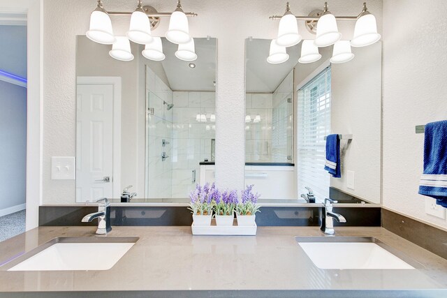 full bath featuring a notable chandelier, a stall shower, vanity, and a textured wall