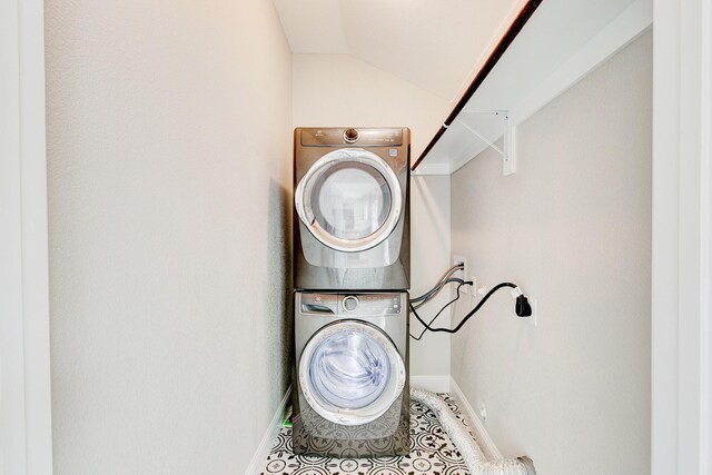 laundry area featuring baseboards, laundry area, and stacked washer / dryer