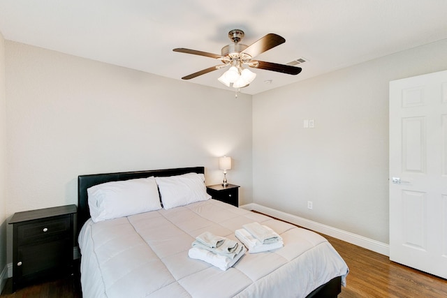 bedroom featuring ceiling fan, wood finished floors, visible vents, and baseboards