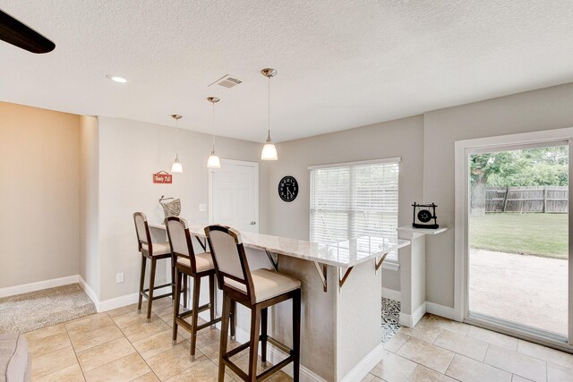 kitchen featuring a healthy amount of sunlight, a textured ceiling, a breakfast bar area, and light stone countertops