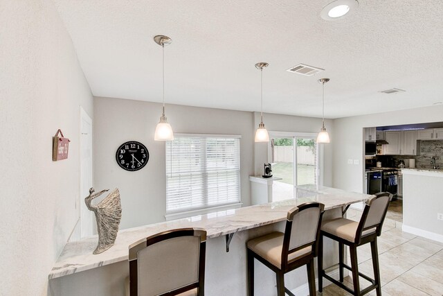 kitchen with visible vents, gas range, tasteful backsplash, and gray cabinetry