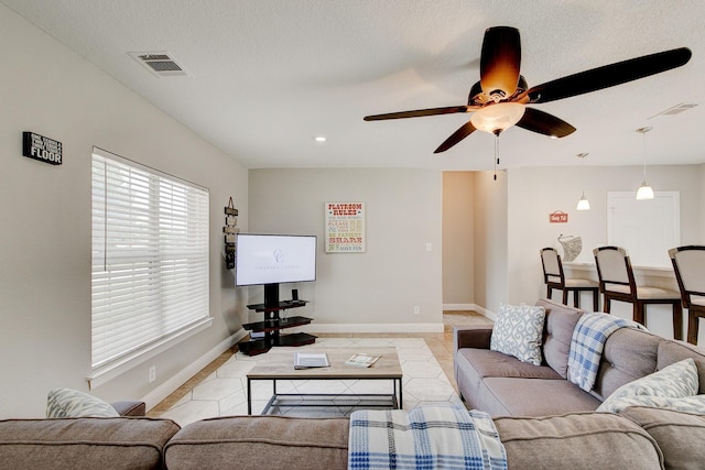 living area with visible vents, baseboards, light tile patterned flooring, and a ceiling fan