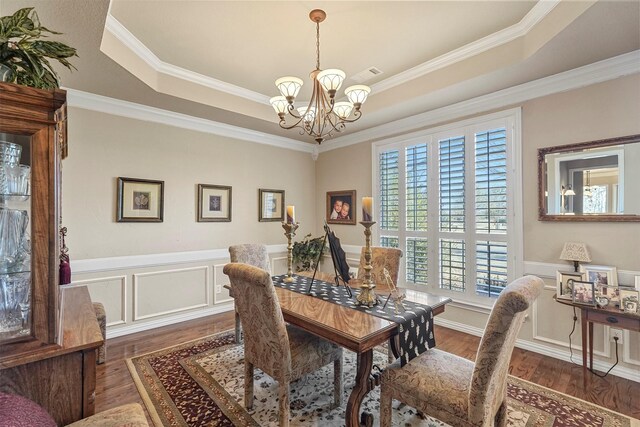 dining room with a chandelier, a raised ceiling, and wood finished floors