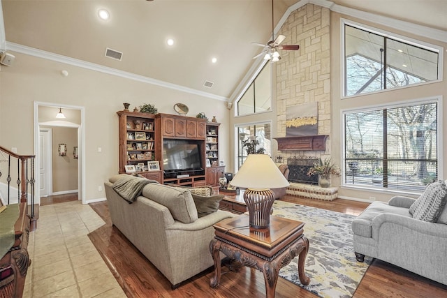 living room with crown molding, a fireplace, visible vents, and a wealth of natural light