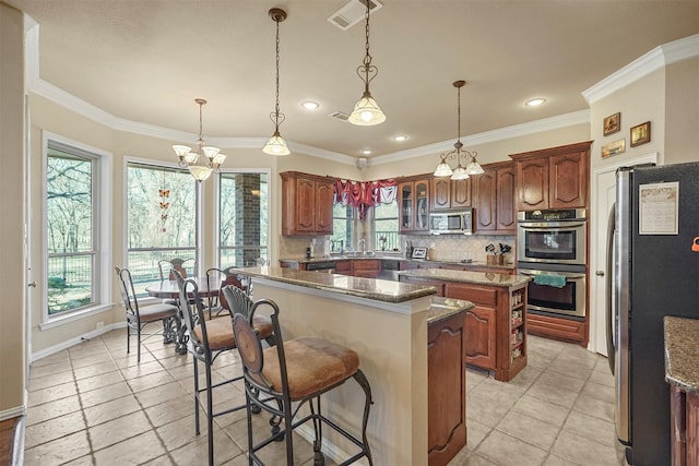 kitchen featuring a kitchen island, ornamental molding, stainless steel appliances, a kitchen bar, and backsplash