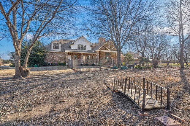 view of front of house with a fenced front yard, brick siding, and a chimney