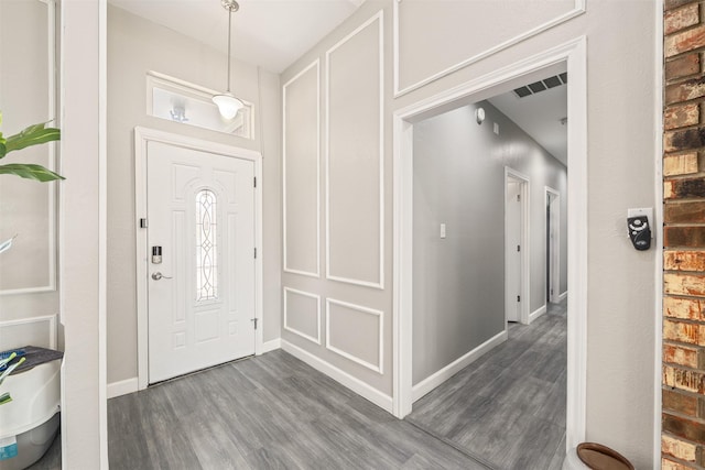 foyer entrance featuring dark wood finished floors, visible vents, and baseboards