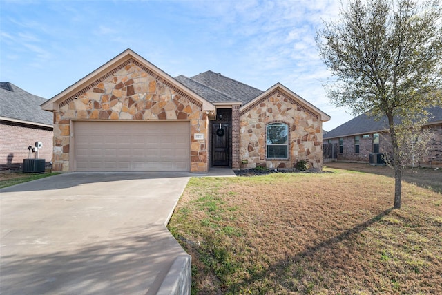 view of front of home featuring a garage, stone siding, central AC, and a front lawn