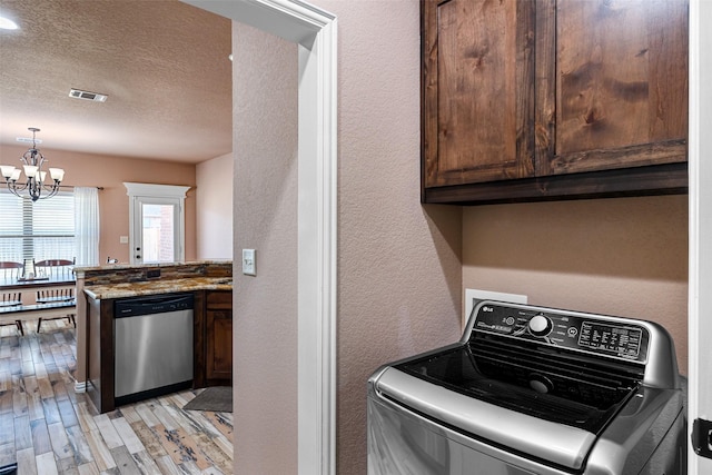 washroom featuring light wood-type flooring, visible vents, washer / clothes dryer, cabinet space, and a chandelier