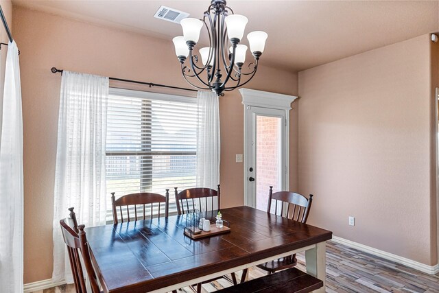 dining room featuring a chandelier, visible vents, baseboards, and wood finished floors