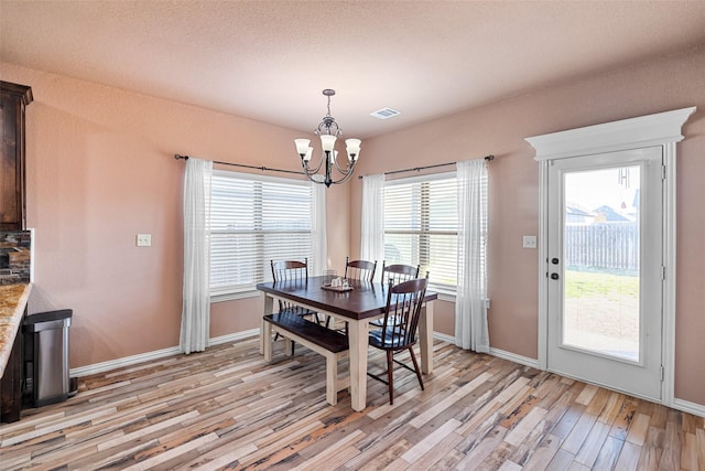 dining room featuring an inviting chandelier, light wood-style flooring, baseboards, and visible vents