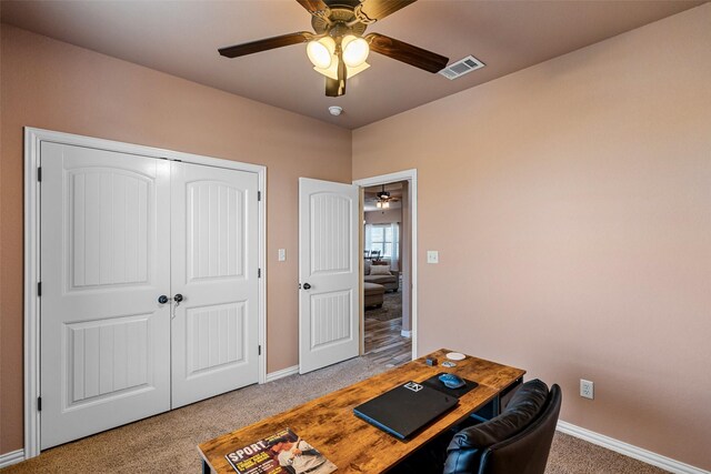 office space featuring light carpet, visible vents, baseboards, and a ceiling fan