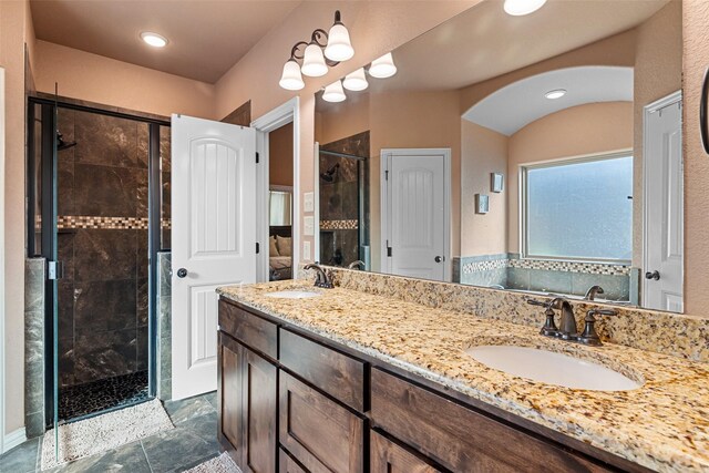 full bathroom with double vanity, a stall shower, and a sink