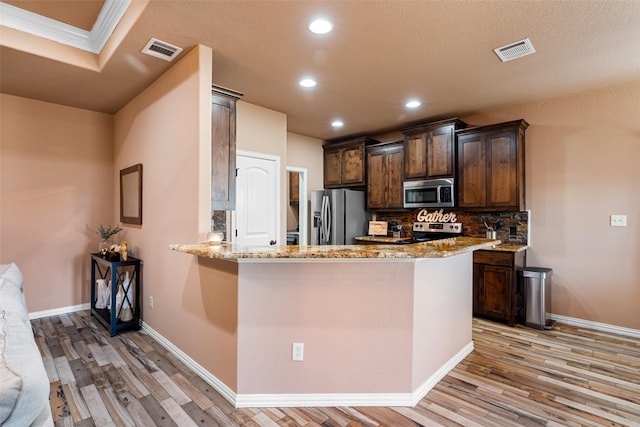 kitchen with visible vents, light wood-style flooring, stainless steel appliances, and decorative backsplash