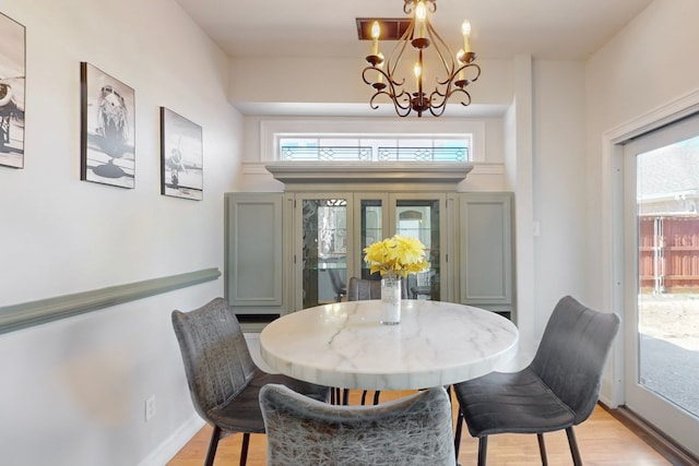 dining space featuring light wood-type flooring, baseboards, and a chandelier