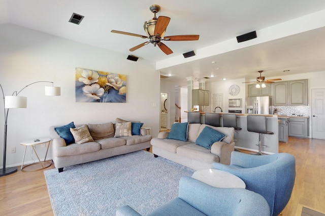 living area with visible vents, ceiling fan, stairs, and light wood-style floors