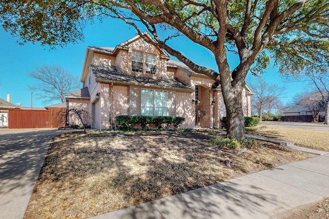 view of front of property featuring fence and brick siding