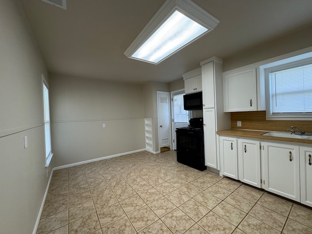 kitchen featuring white cabinetry, black appliances, light tile patterned flooring, and a sink