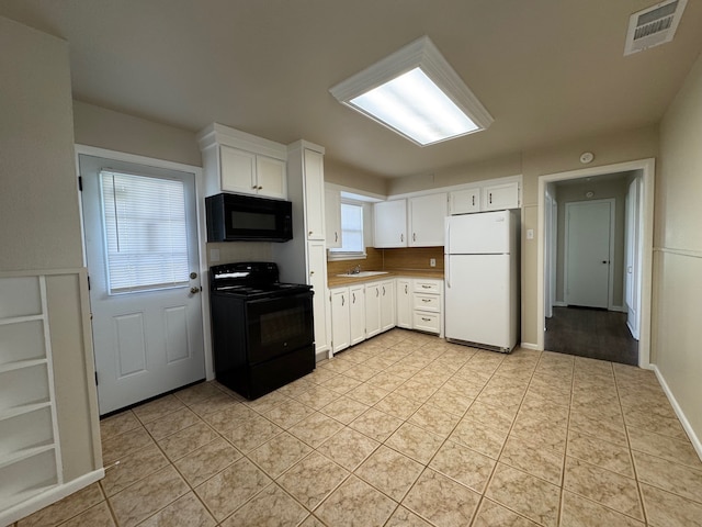 kitchen featuring visible vents, light tile patterned floors, white cabinets, black appliances, and a sink